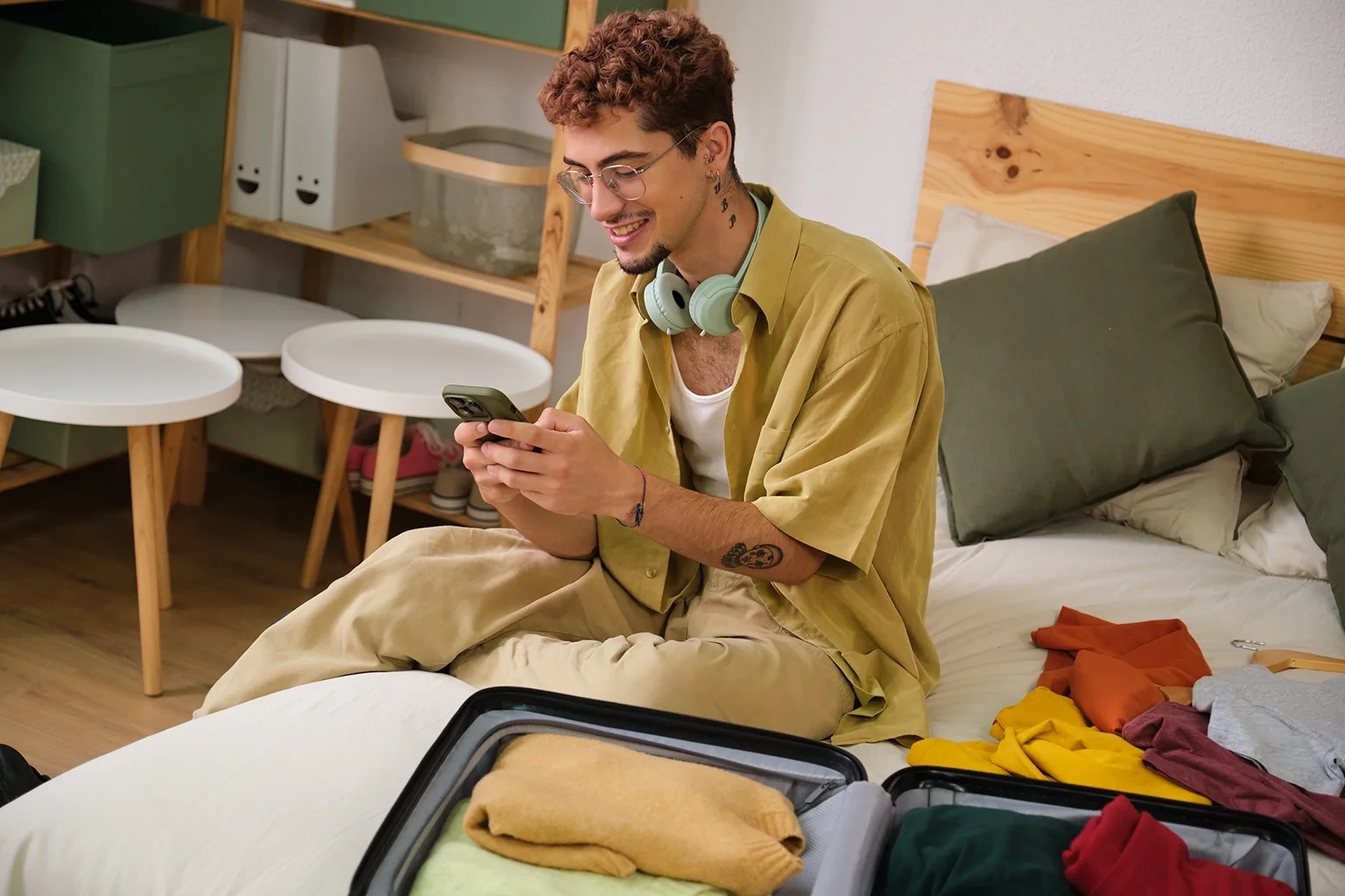 joven viendo su celular mientras hace maleta para viaje